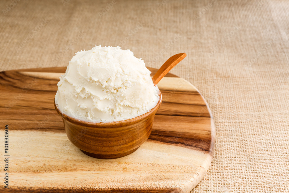 Shea butter in the wooden bowl stands on the wooden board, on th Shea butter in the wooden bowl stands on the wooden board, on th