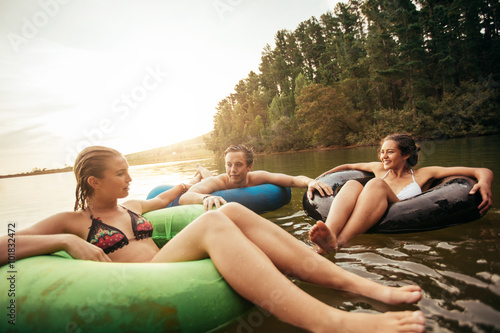 Friends floating on lake with inflatable rings © Jacob Lund