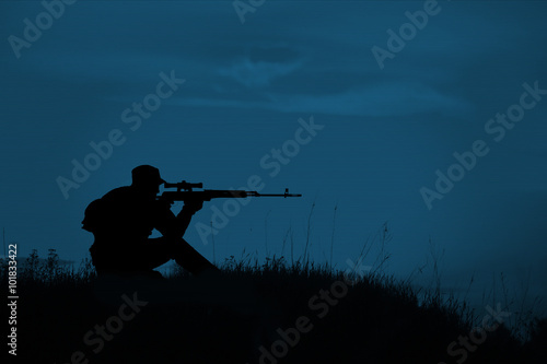 Silhouette of military sniper with sniper rifle at night. shot, photo
