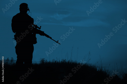 Silhouette of military sniper with sniper rifle at night. shot