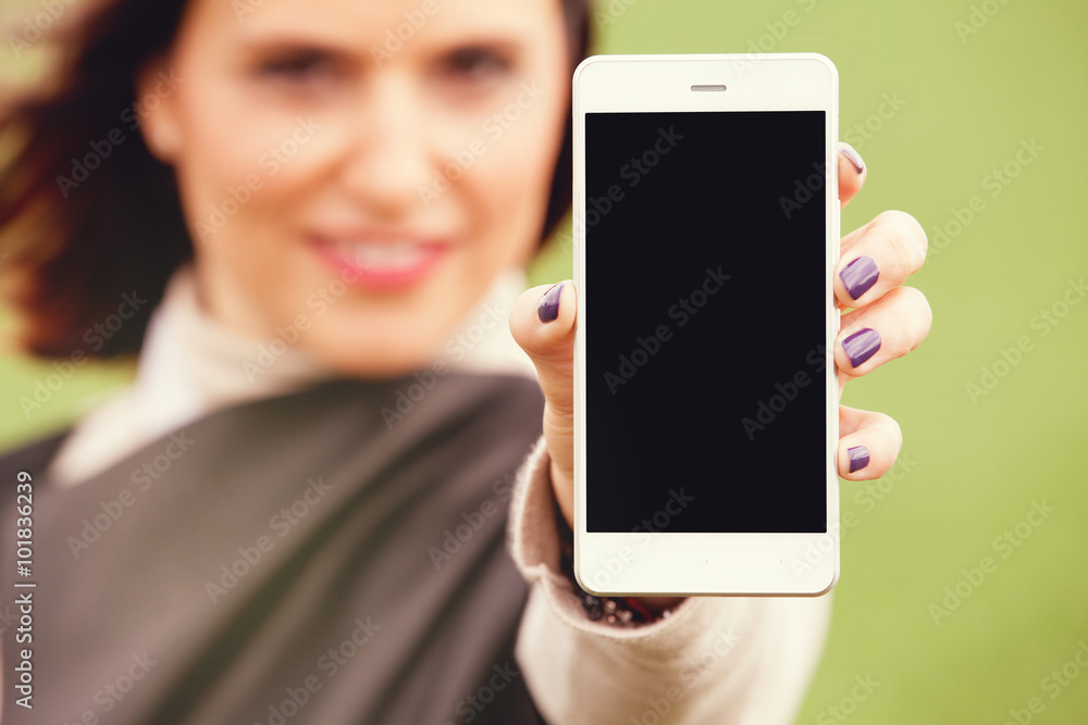 Woman showing mobile phone screen to the camera. Cropped image of cute woman with smart phone in the foreground. Black Screen.