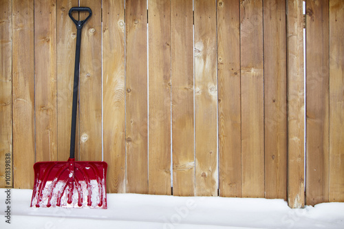 snow shovel leaning agains a fence
