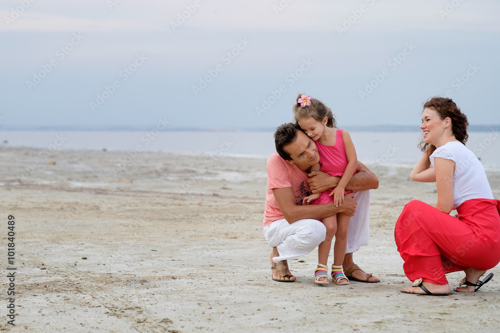 Happy family of three having fun sitting in the sand on beach Happy family of three having fun sitting in the sand on beach