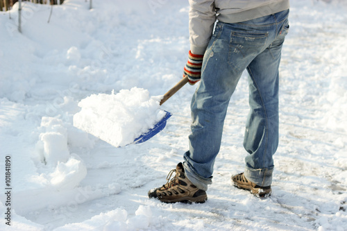 man cleans the track from snow shoveling, sunny winter day
