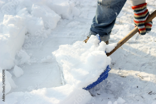 man cleans the track from snow shoveling, sunny winter day