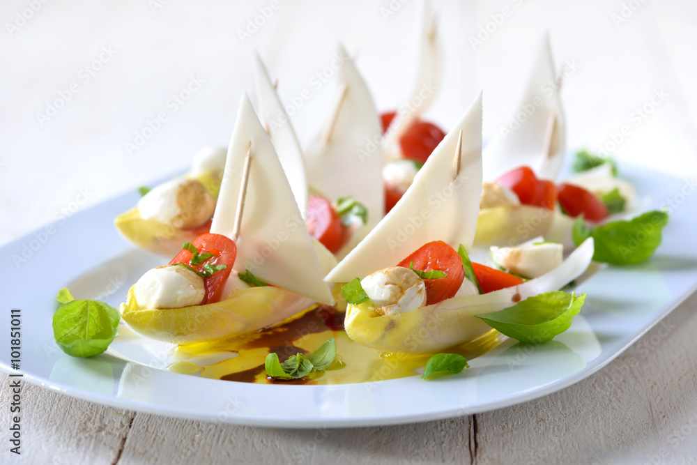 Chicoree-Schiffchen mit Caprese-Füllung: Minitomaten und Mozzarella-Bällchen; Chicory leaves stuffed with cherry tomatoes and mozzarella balls Chicoree-Schiffchen mit Caprese-Füllung: Minitomaten und Mozzarella-Bällchen; Chicory leaves stuffed with cherry tomatoes and mozzarella balls