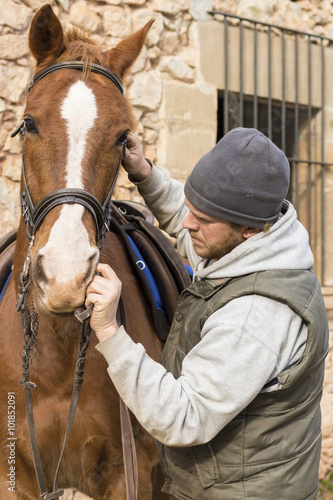 Man puts bridle on a horse.