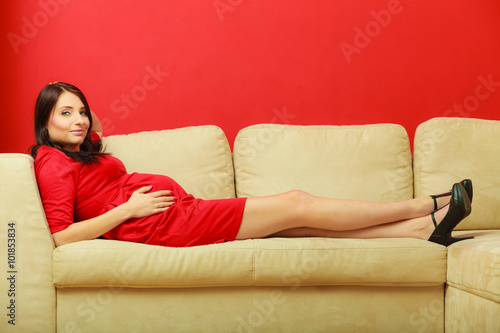 pregnant woman relaxing on sofa touching her belly
