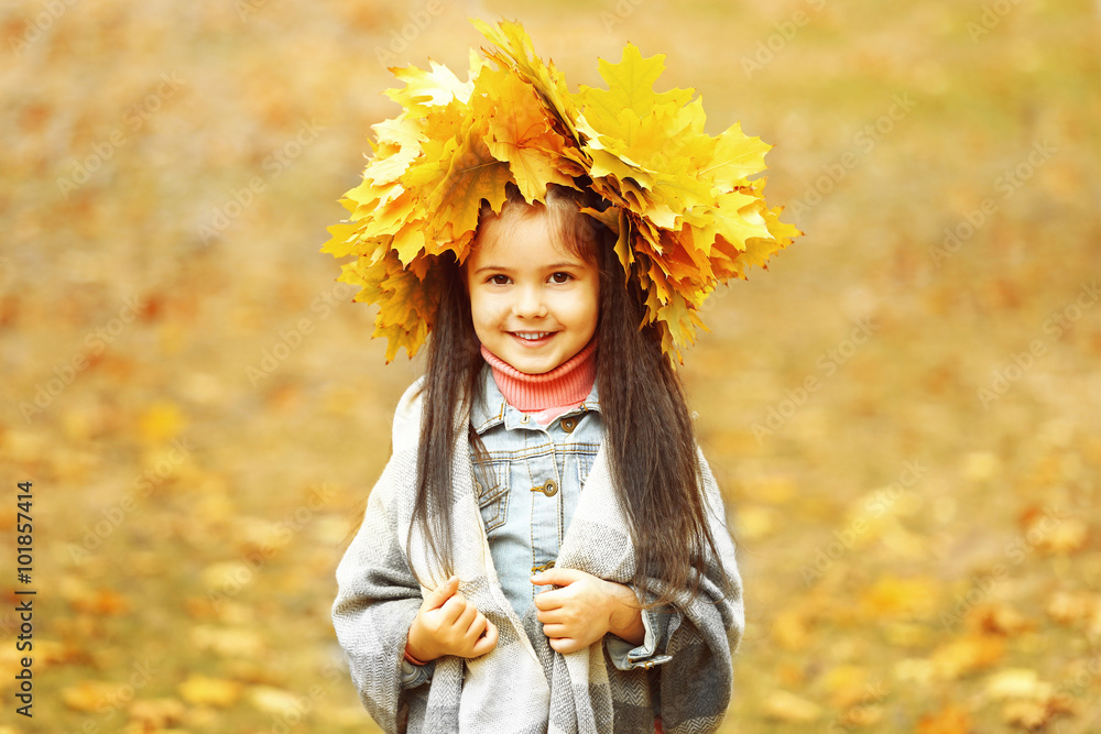 Fototapeta premium Happy young girl in yellow autumn wreath in park
