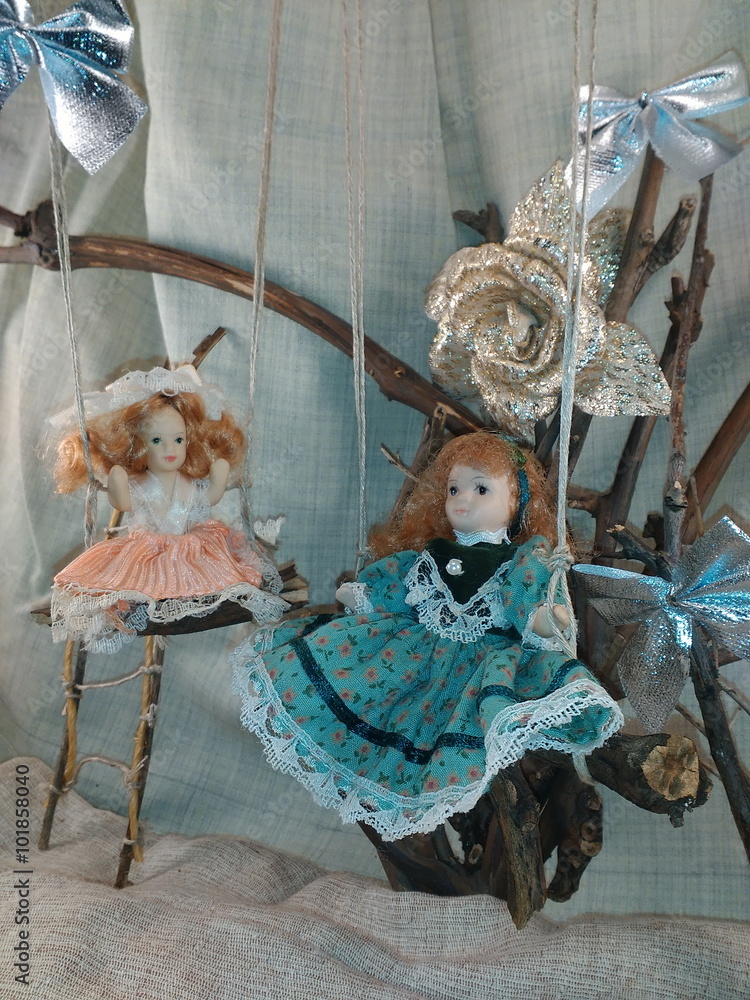 Porcelain dolls on swings photo. Two pretty porcelain dolls on swings photo. 