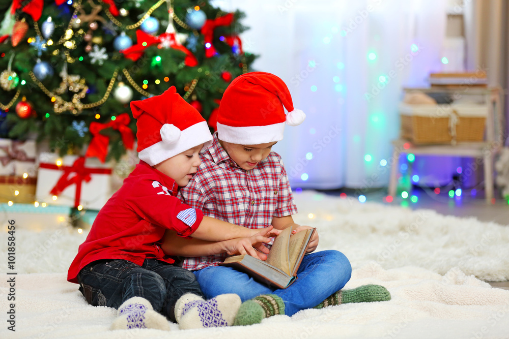 Two cute small brothers reading book on Christmas decoration background Two cute small brothers reading book on Christmas decoration background