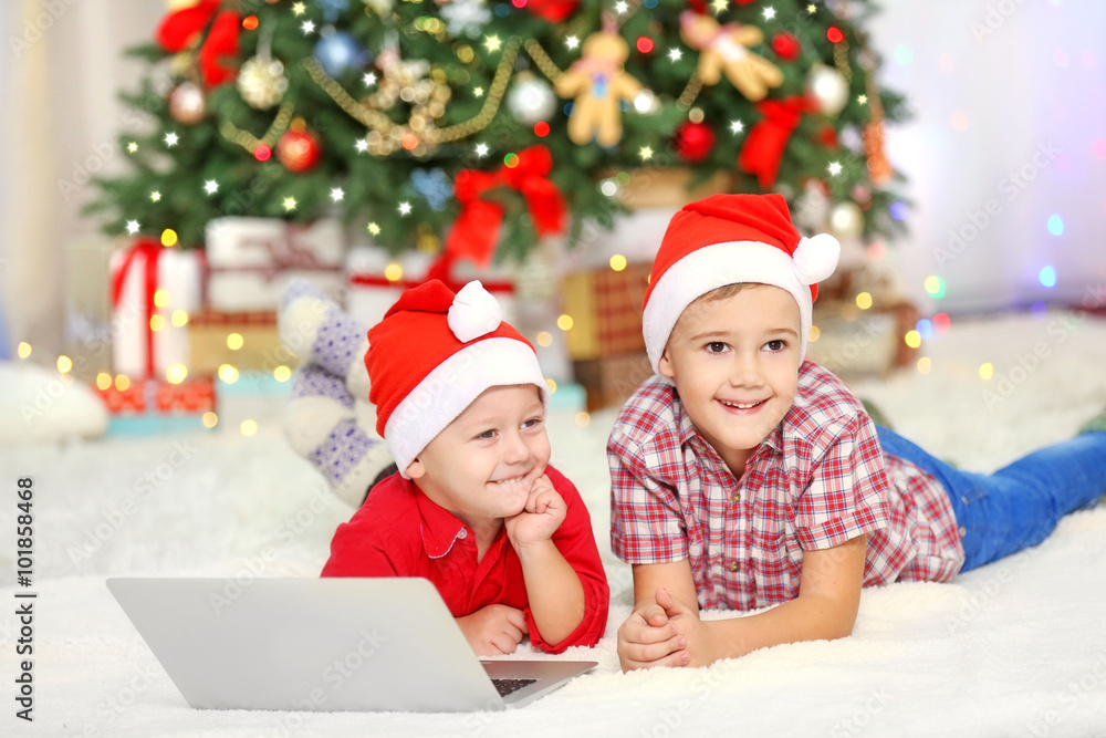 Two cute small brothers using laptop on Christmas decoration background Two cute small brothers using laptop on Christmas decoration background