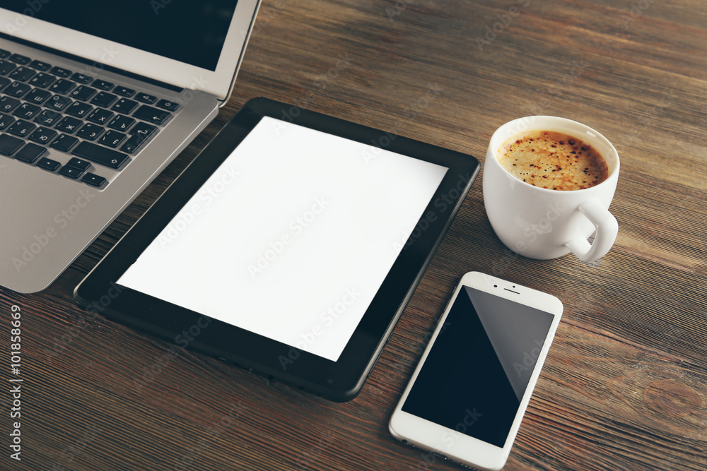 Modern laptop, mobile phone, tablet and coffee cup on wooden table, close-up Modern laptop, mobile phone, tablet and coffee cup on wooden table, close-up