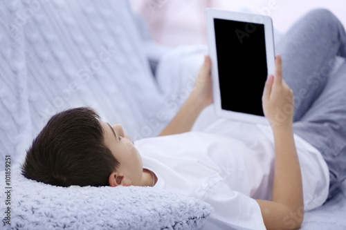 Boy using tablet on a sofa ...