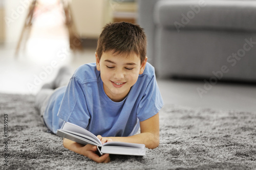 Boy reading book on a floor...