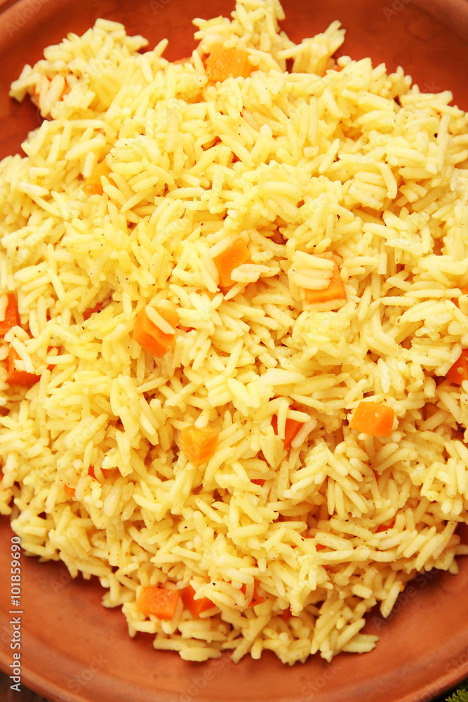 Stewed rice with a carrot on a brown plate, close up Stewed rice with a carrot on a brown plate, close up