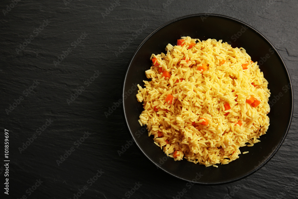 Stewed rice with a carrot on a plate over black background Stewed rice with a carrot on a plate over black background