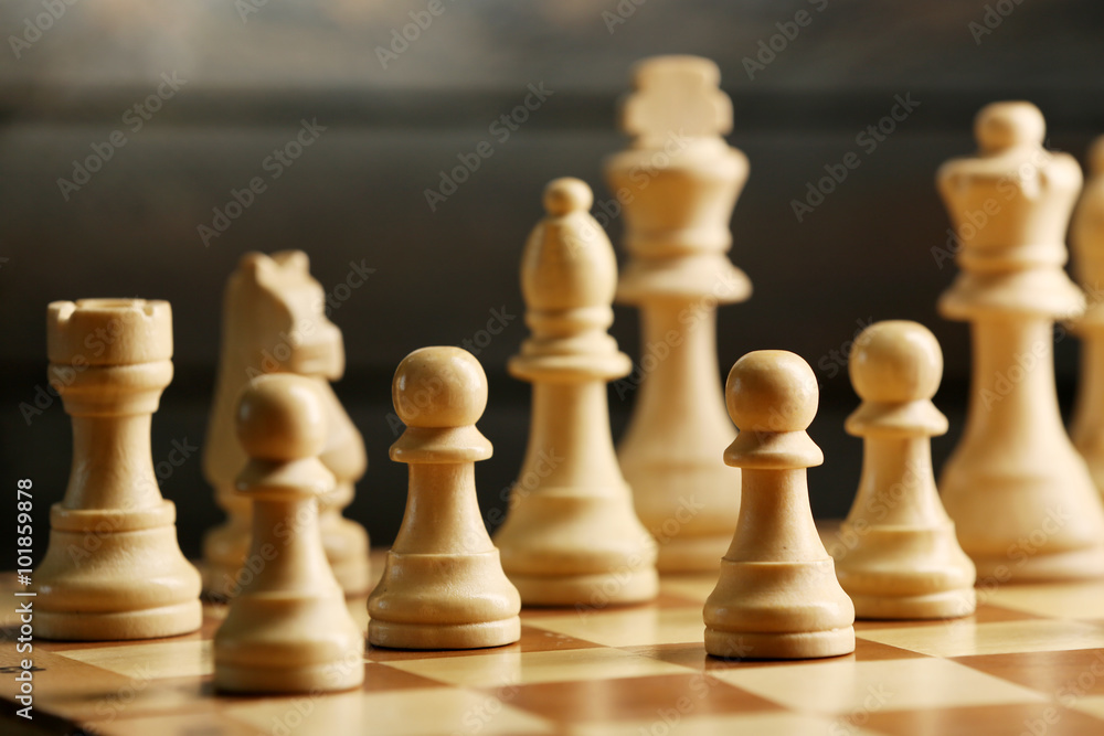 Chess pieces and game board on wooden background