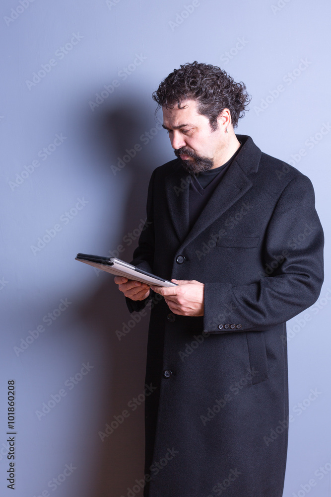 Man Wearing Trench Coat Reading from Tablet Man Wearing Trench Coat Reading from Tablet