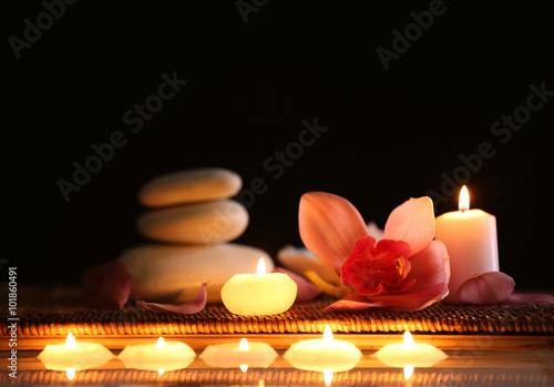 Fototapeta Naklejka Na Ścianę i Meble -  Spa still life with stones, candles and flowers in water on black background