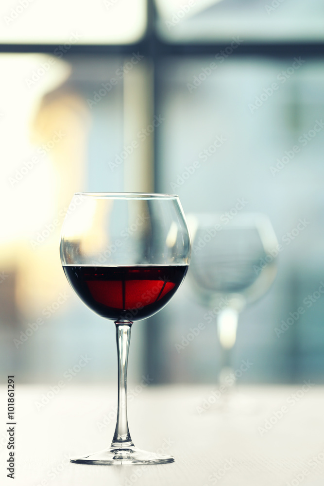 Glass of red wine on light blurred background Glass of red wine on light blurred background