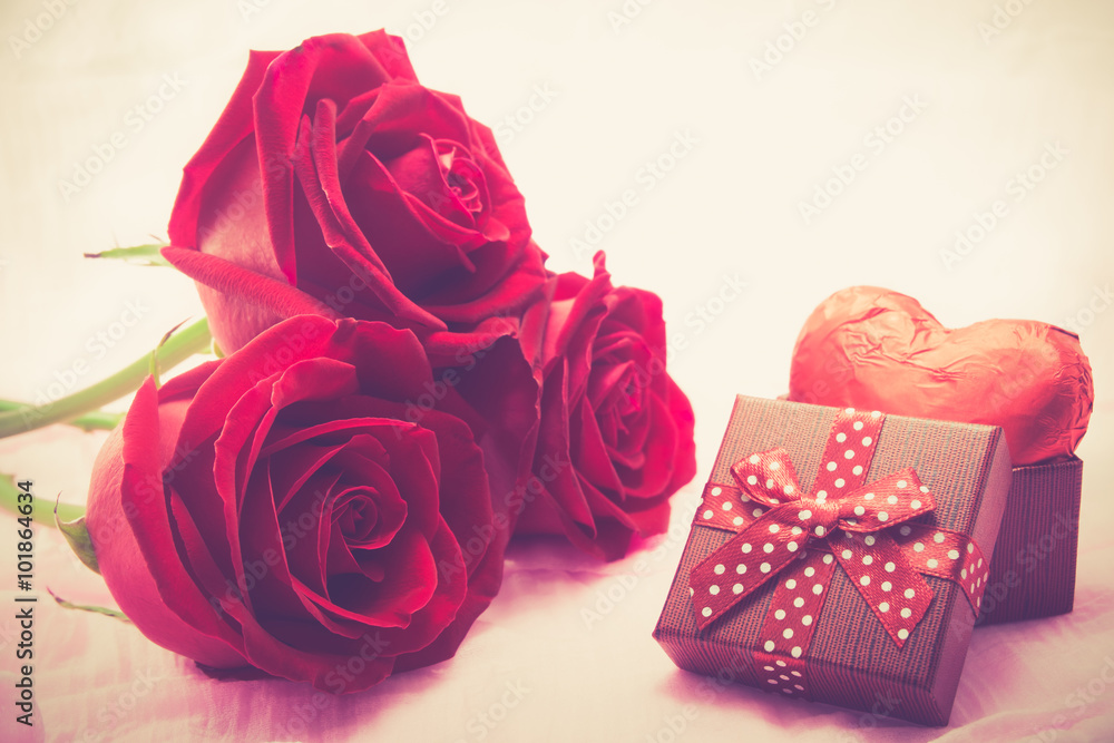 Red roses and chocolate heart shape presents on fabric