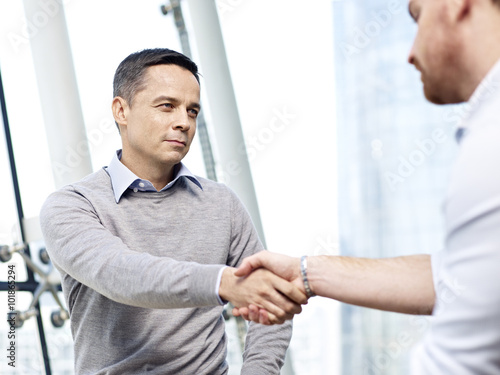 businessman shaking hands with competitor