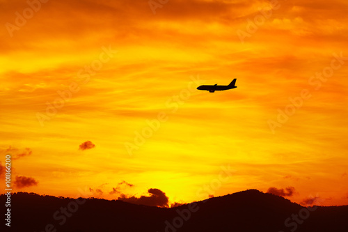 Beautiful Landscape. Travel On Summer Vacations To Thailand, Asia. Silhouette Of Flying Aircraft ( Airplane ) In Beautiful Orange Sky, Hills Of Tropical Island During Sunset. Tourism. Transportation.