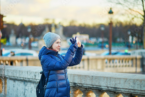 Happy young tourist taking a photo in Paris, France on a winter day