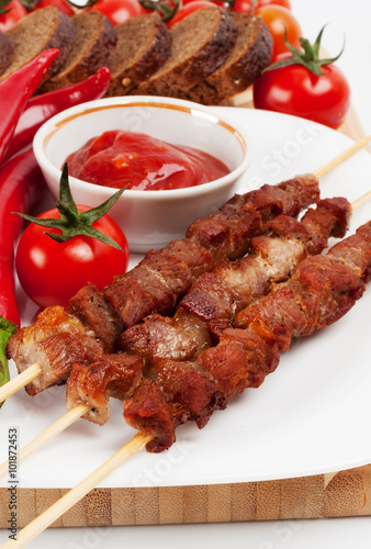 Shish kebab on bamboo sticks on white plate