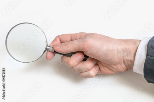 Man's hand holds magnifier or magnifying glass.