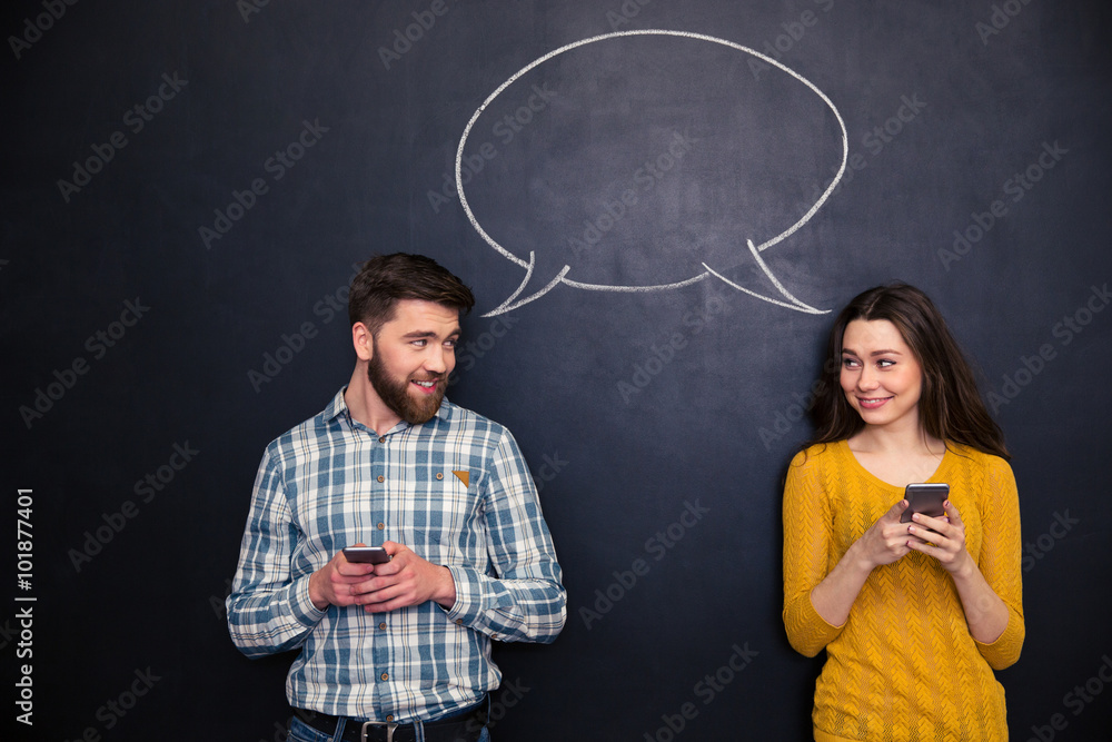 Couple using smartphones over blackboard with speech dialogue