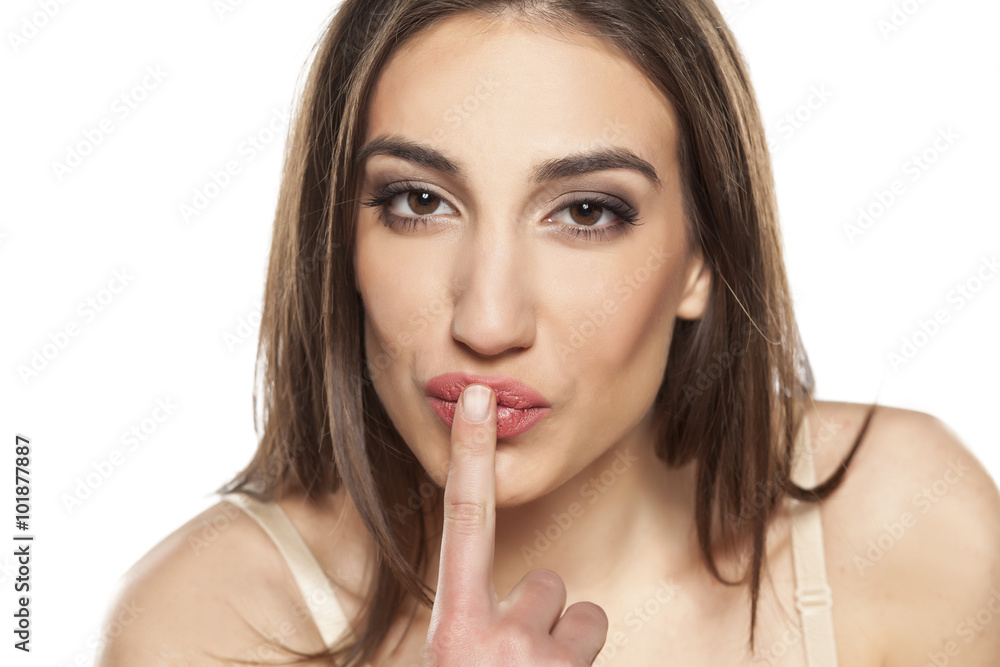 portrait of a beautiful young woman kissing her finger portrait of a beautiful young woman kissing her finger