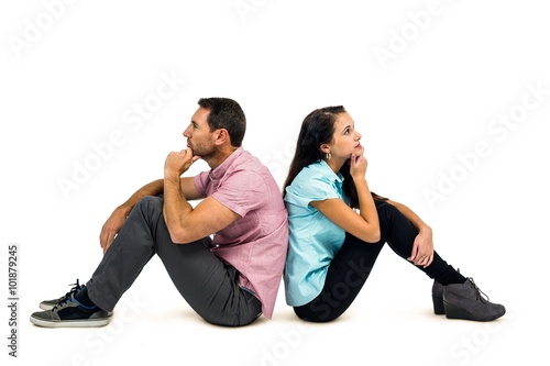 Thoughtful couple sitting on the floor back to back