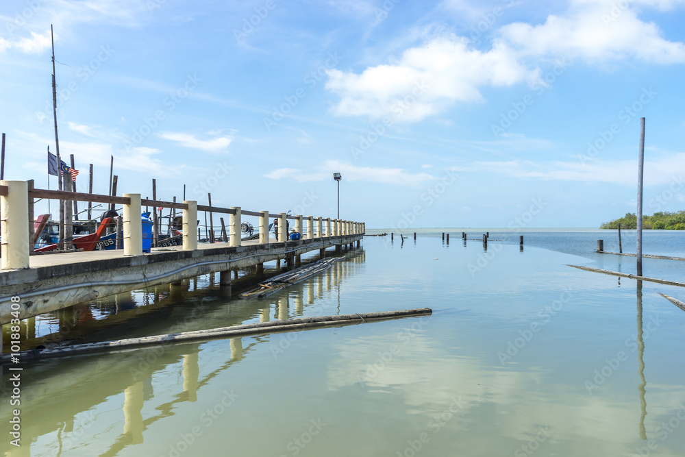 Jetty with blue skies and reflection at Leka Beach (Pantai Leka) at Muar, Johore.