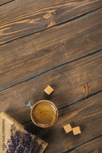 Cozy morning concept: cup of coffee, vintage book and dry lavender bunch over brown rustic background. Space for text