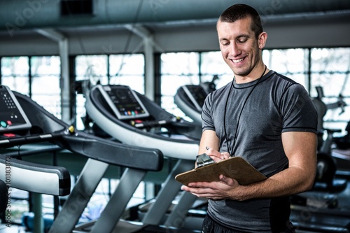 Muscular trainer writing on clipboard