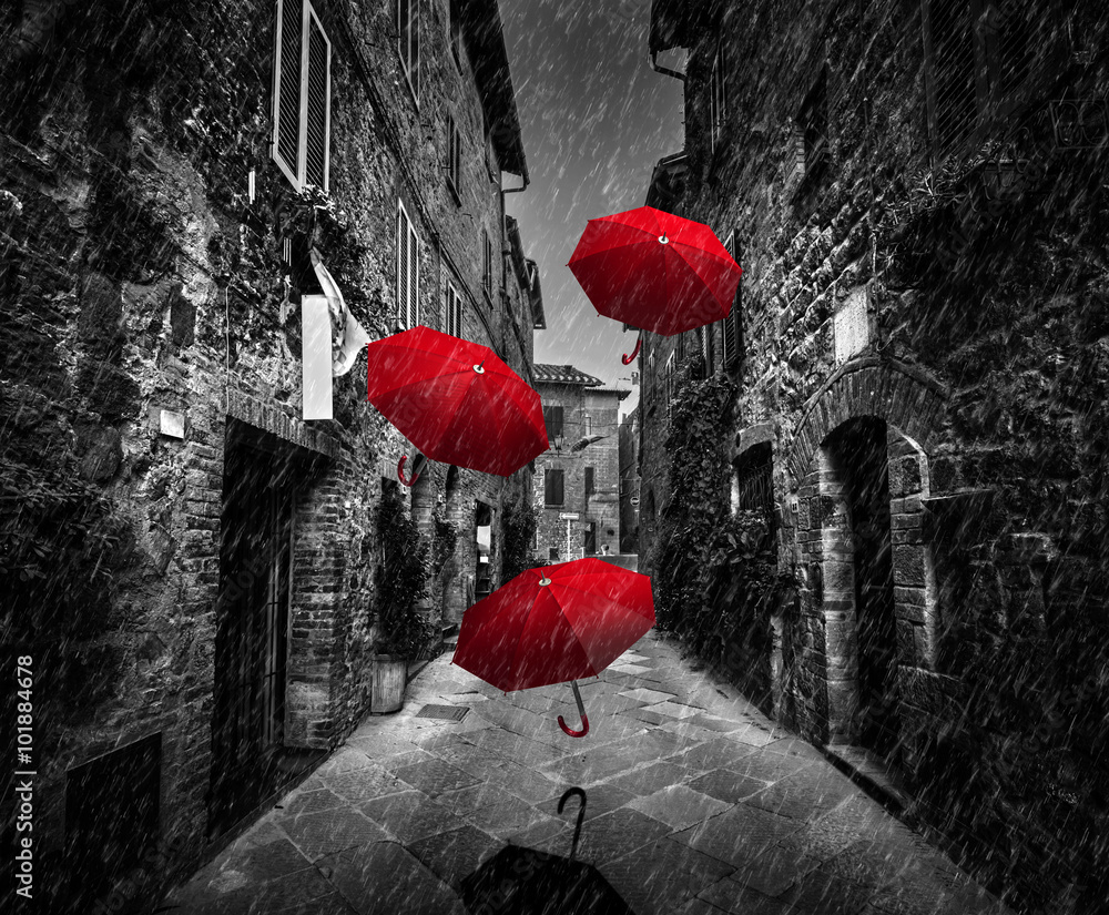 Fototapeta premium Umrbellas lata z wiatrem i deszczem na ciemnej ulicie w starym Włoskim miasteczku w Tuscany, Włochy