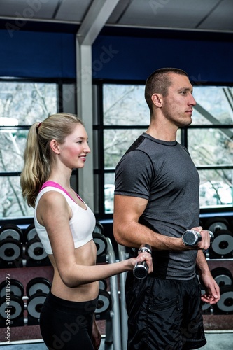 Smiling fit couple lifting dumbbells 