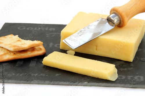 Fresh cut cheddar cheese with crackers on a slate board