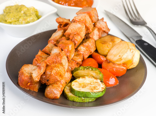 skewered meat and vegetables on plate on white background