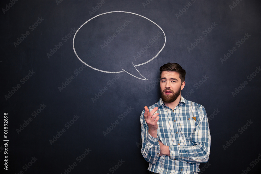 Bearded man talking over blackboard background with drawn speech bubble Bearded man talking over blackboard background with drawn speech bubble