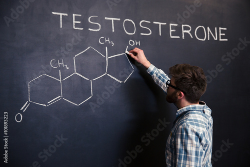 Fotografía Concentrated student drawing chemical structure of testosterone molecule on blac
