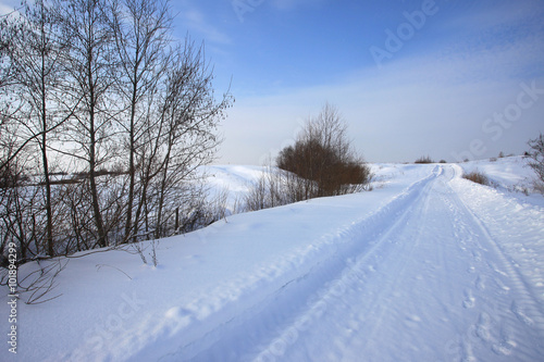 Winter snowy rural road and blue sky landscape © larineb