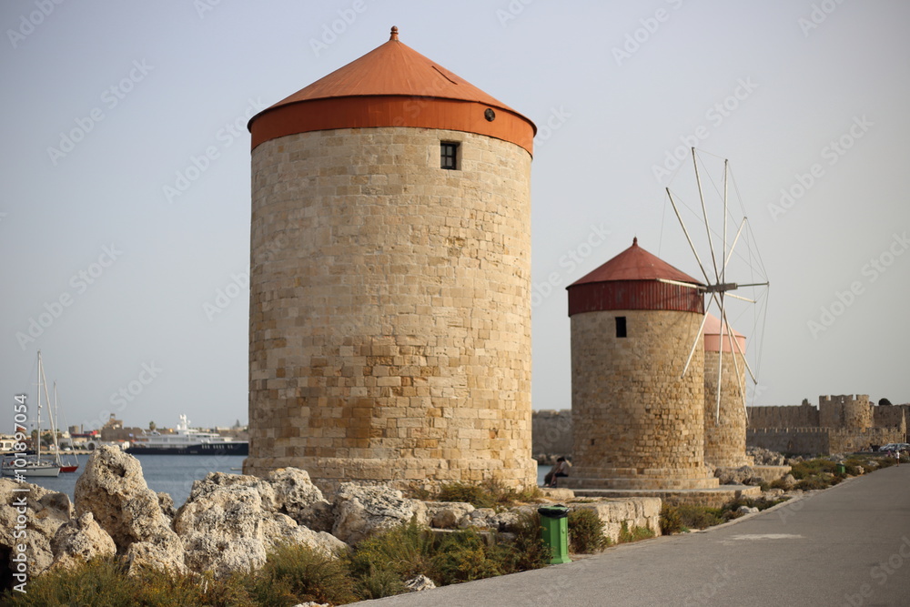 Windmills in the port of Rhodes, Greece.The historic windmills at the Mandraki harbor in Rhodes town. Rhodes Island, Greece. Rhodes, Mandraki port on sunset. Greece.