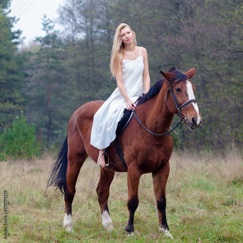 romantic sensual girl in white dress on a horse in the forest