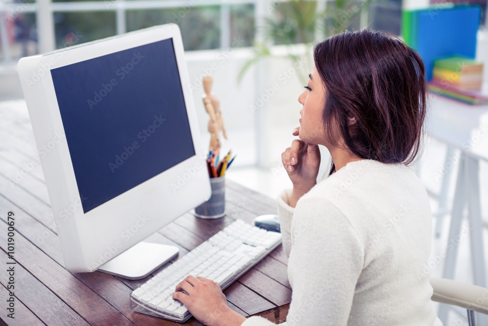 Asian woman on computer with finger on chin Asian woman on computer with finger on chin