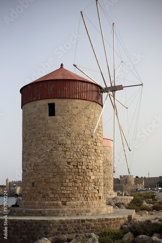 Windmills in the port of Rhodes, Greece. The historic windmills at the Mandraki harbor in Rhodes town. Rhodes Island, Greece. Rhodes, Mandraki port on sunset. Greece.