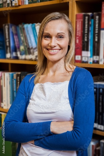 Smiling female student with arms crossed in the library