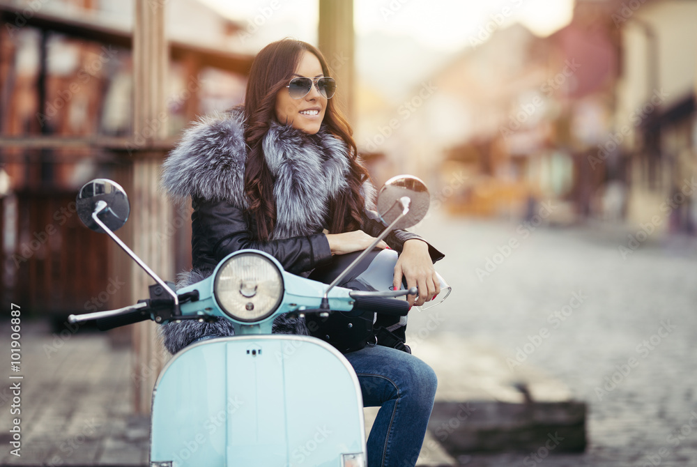 City lifestyle. Cute young woman siting on her Vespa scooter, looking at  side and smiling. Beautiful warm sunset color in background. Stock Photo |  Adobe Stock